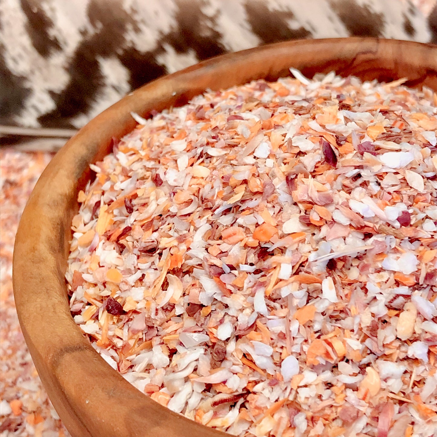A wooden bowl filled with orange, purple, and white crushed mano de lion shells. Also, known as "paw of the lion", these tiny shell fragments are 0.25 to 2 millimeters.