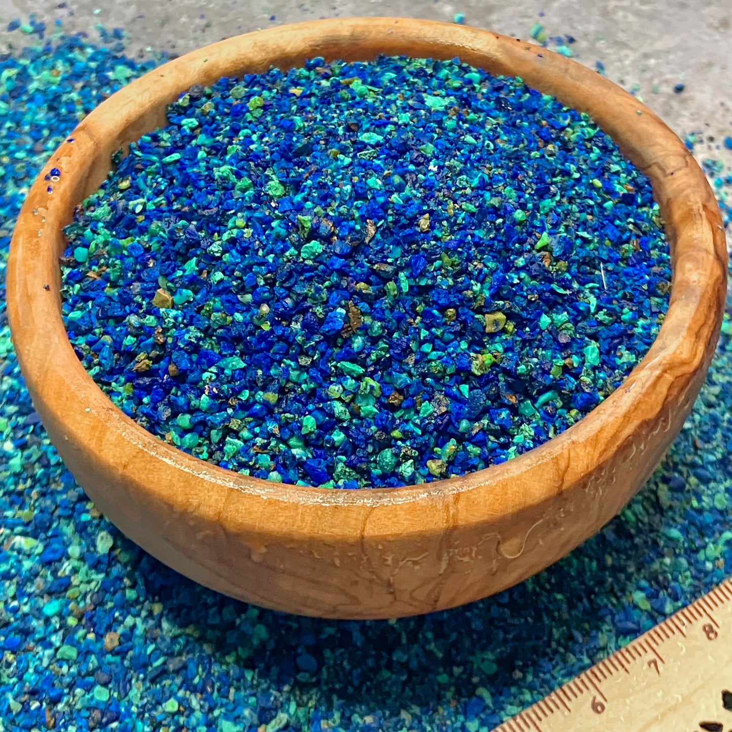Crushed azurite and malachite sand sized particles in a small wooden bowl.